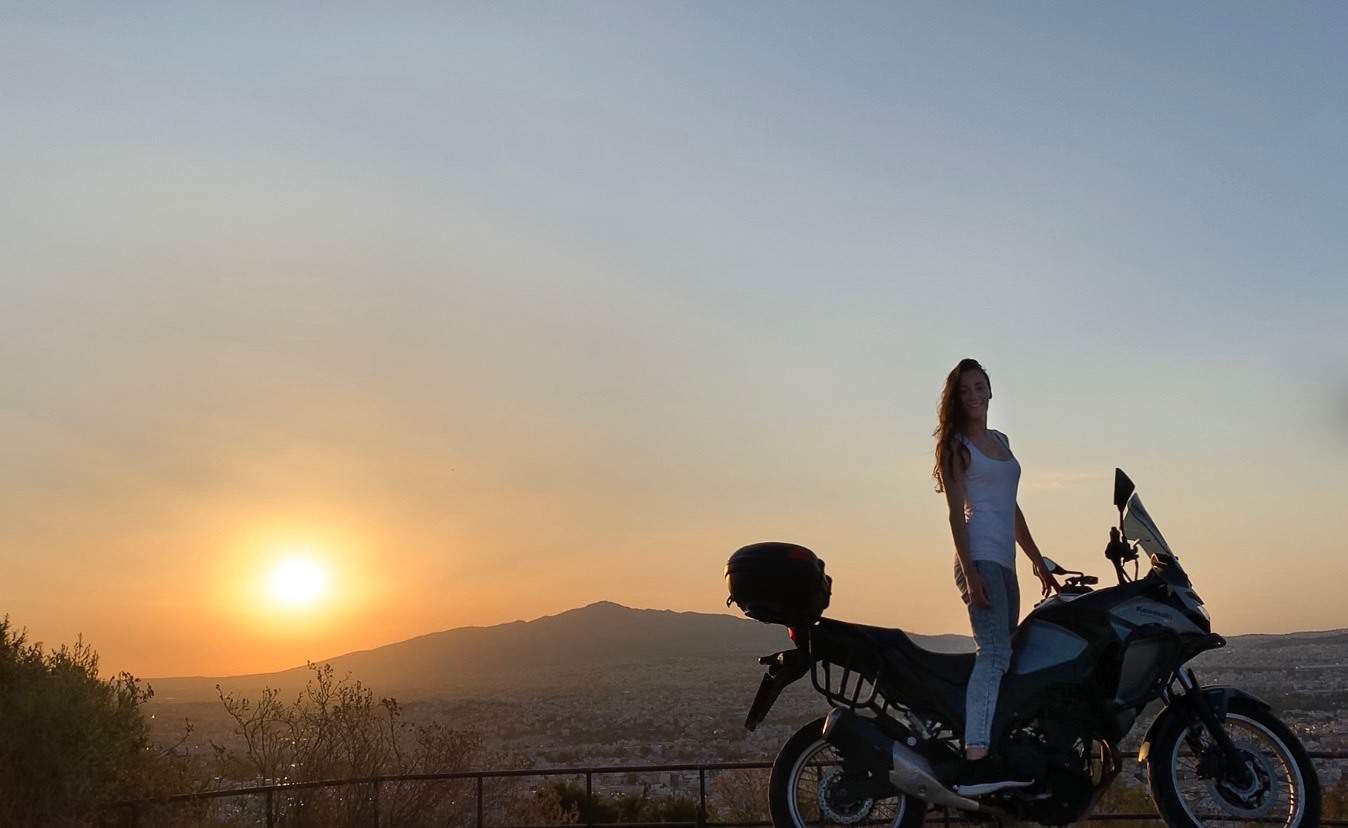 woman traveling on motorcycle with sunrise behind her